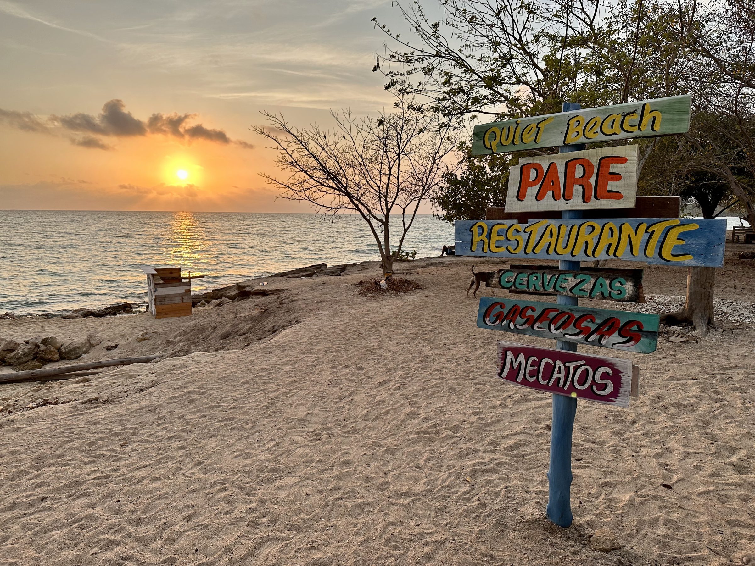A hand-painted sign for a small beach restaurant at sunset. Spending locally keeps the benefits of travel in town.